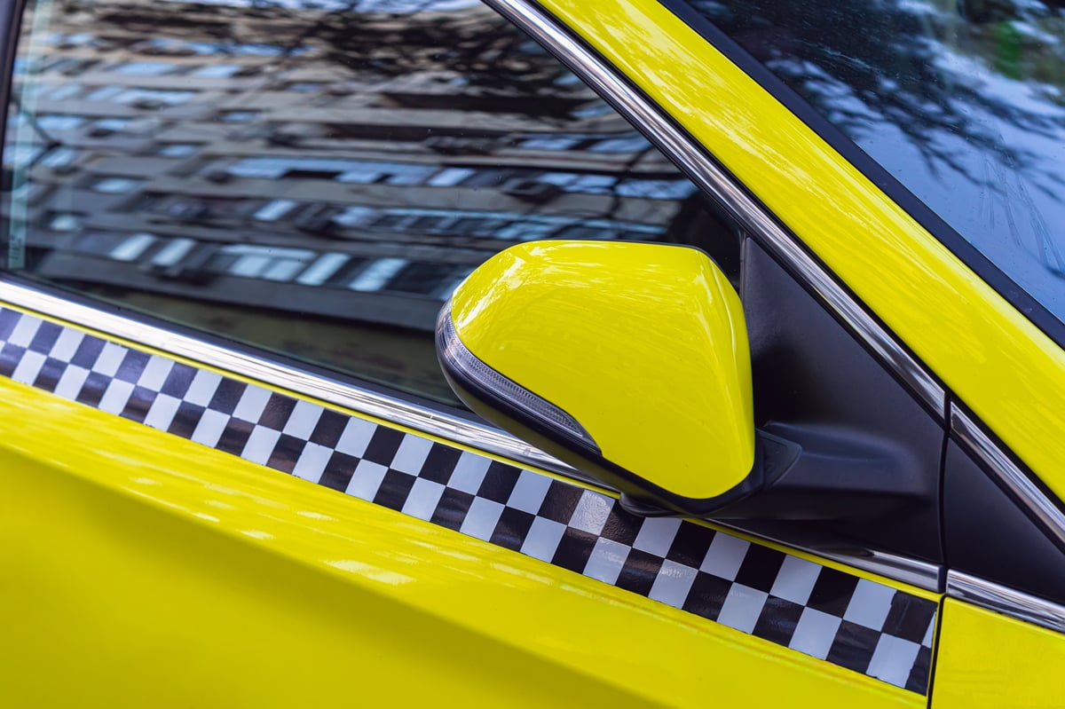 Detalle de la puerta de un taxi con la banda de cuadros amarilla y negra